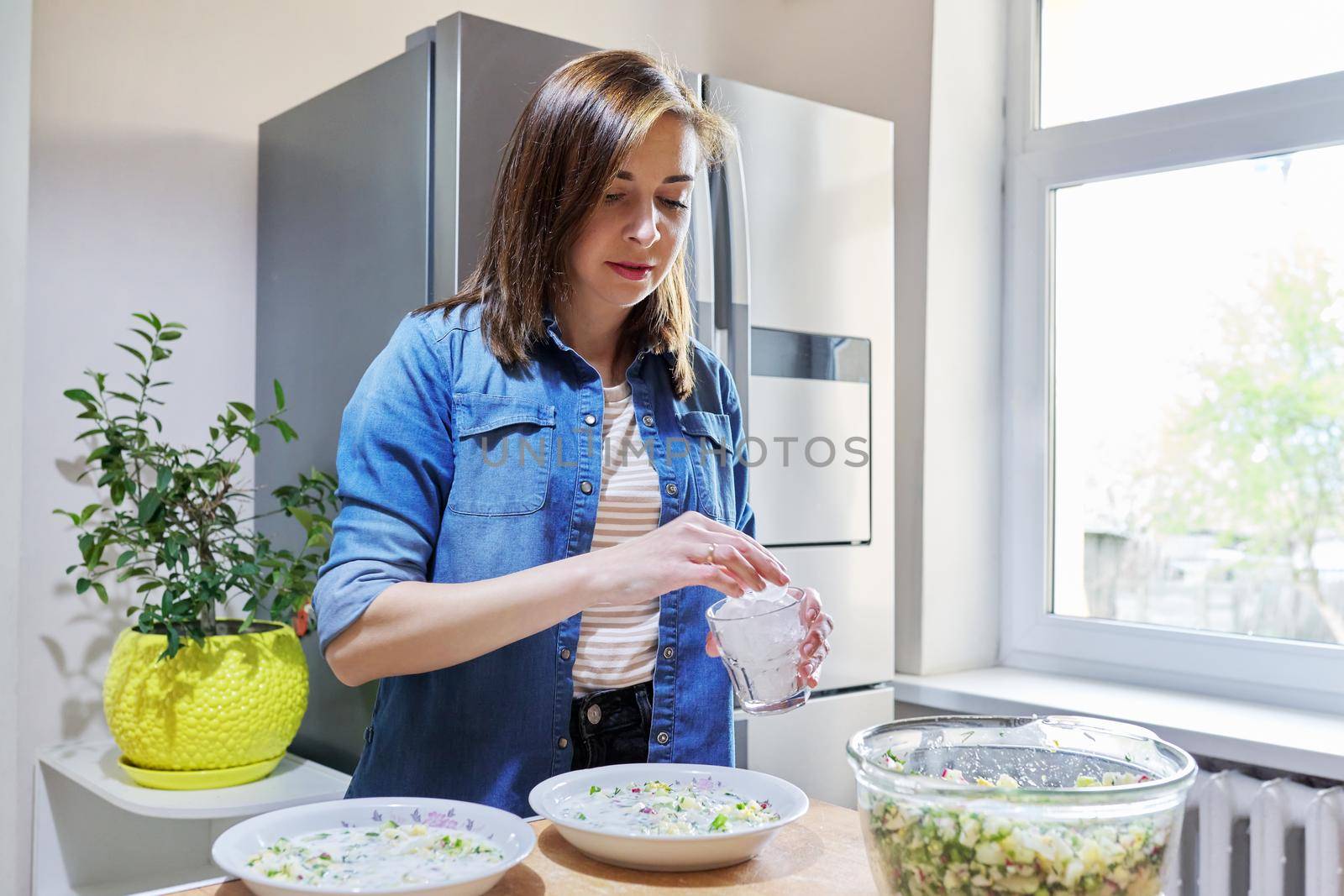 Woman in kitchen near refrigerator with ice for cooling food by VH-studio