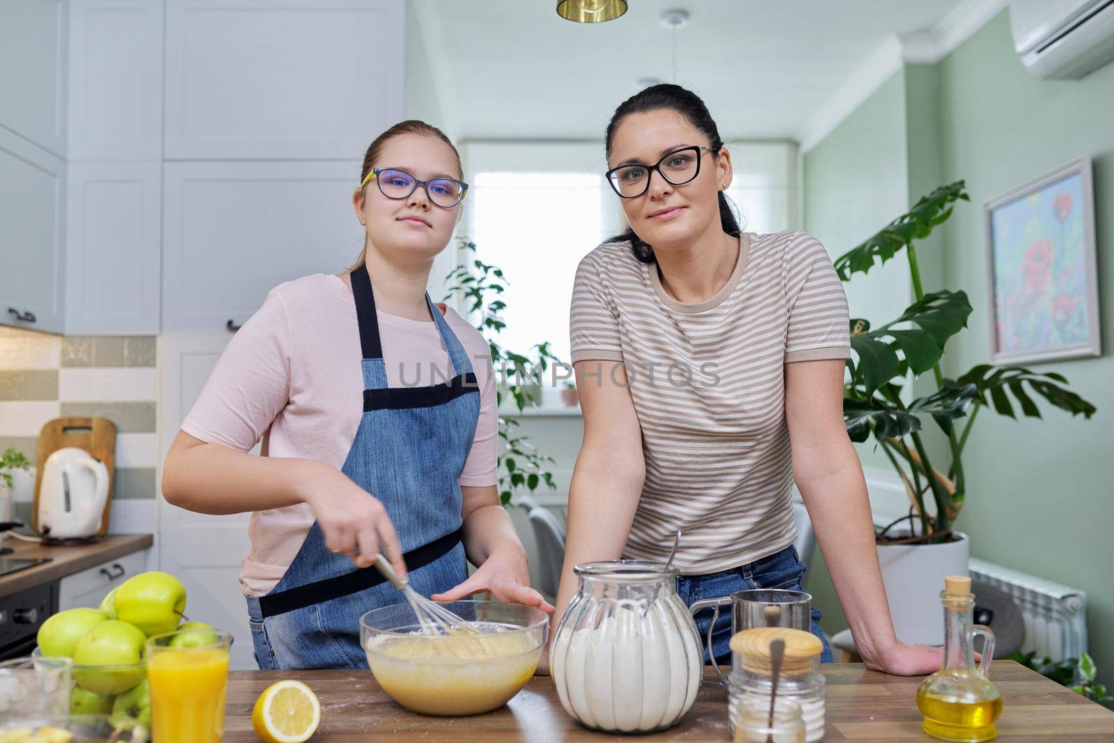 Mom and daughter 12, 13 years old cook together apple pie, mother teaches girl cooking, parent-teen communication, lifestyle, eat at home concept