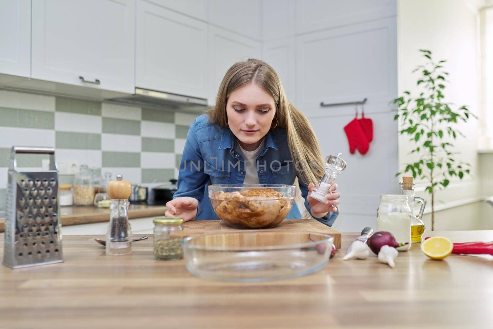 Chicken cooking process, recipe, food blog, food for the holiday. Young woman in the home kitchen preparing meat, chicken