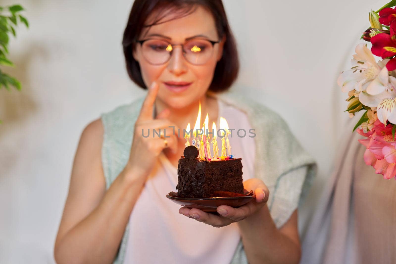 Mature beautiful woman with small birthday cake with burning candles by VH-studio
