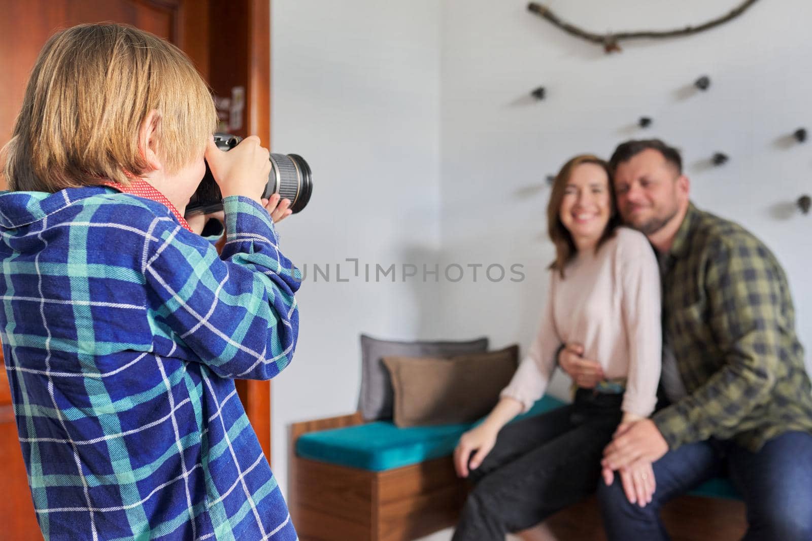 Happy family at home, little son with camera taking photo of hugging parents. Family, lifestyle, relationships, leisure, home life concept