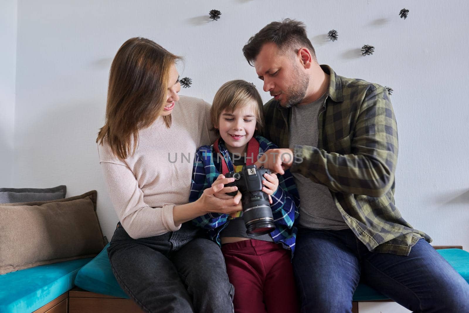 Happy family at home, little son with photo camera with mom and dad. Family, lifestyle, relationships, leisure, home life concept
