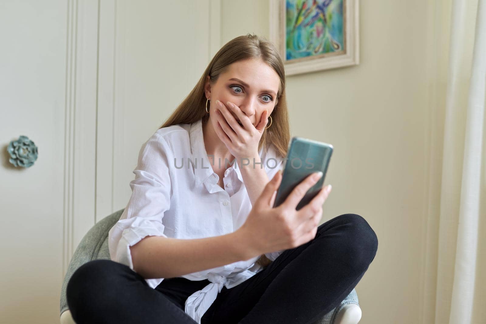 Emotional young beautiful woman looking at smartphone screen by VH-studio