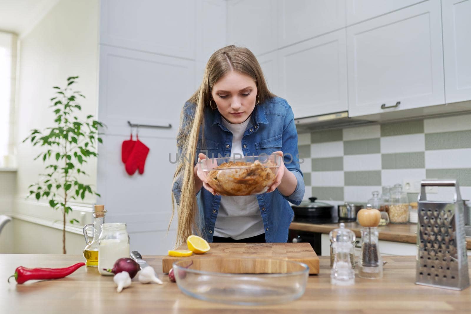 Chicken cooking process, recipe, food blog, food for the holiday. Young woman in the home kitchen preparing meat, chicken