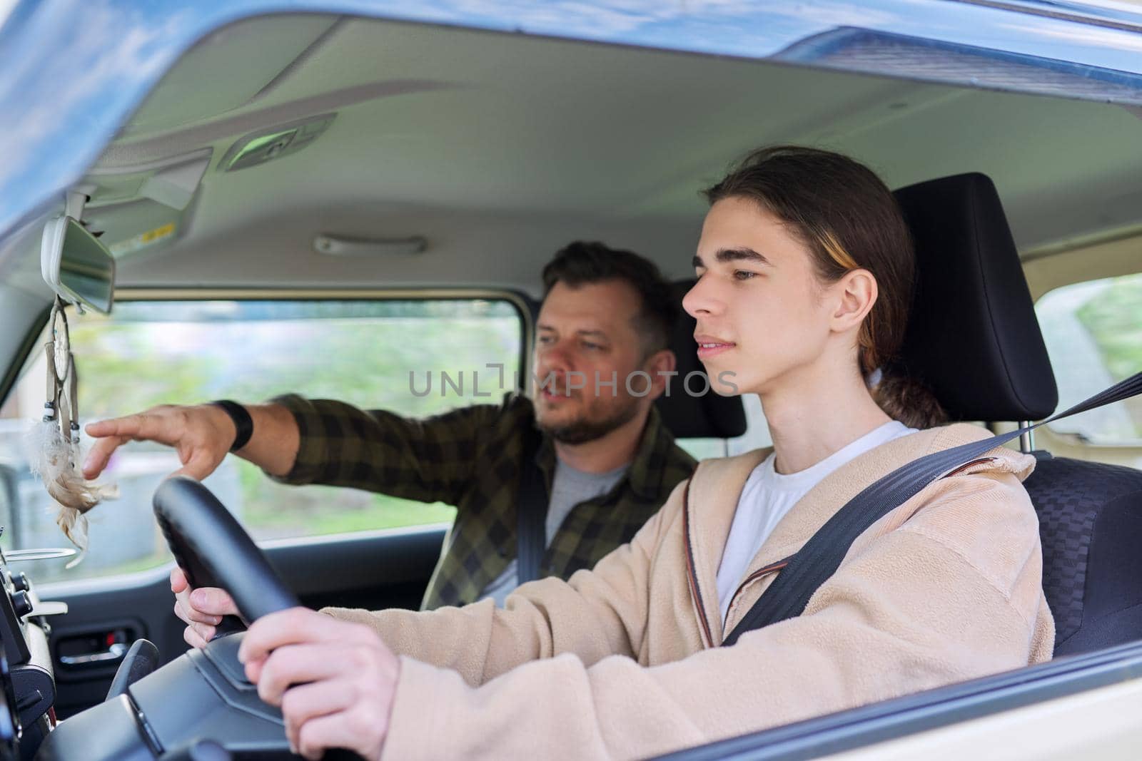 Father teaching his teenage son to drive. Family, relationship middle aged parent teenager, friendship of father and son