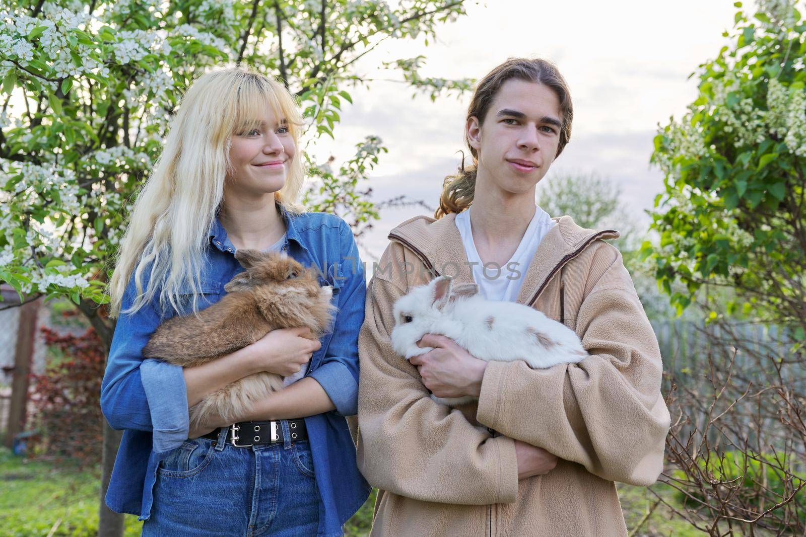 Teenagers with rabbits in their hands, pets a couple of decorative rabbits by VH-studio