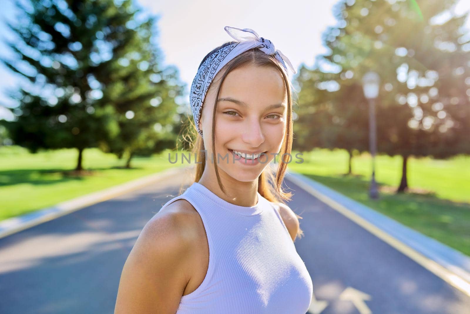 Portrait of beautiful smiling young female outdoors. Hipster teenager on sunny summer day, on the road in the park. Teens, people, age, youth concept