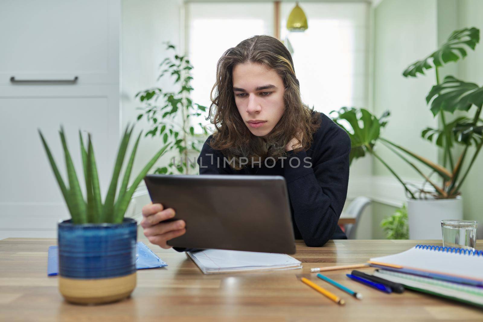 Online lesson, guy student teenager studying at home remotely using digital tablet. E-learning, tele technology, e-education, teenagers, distance education, high school concept