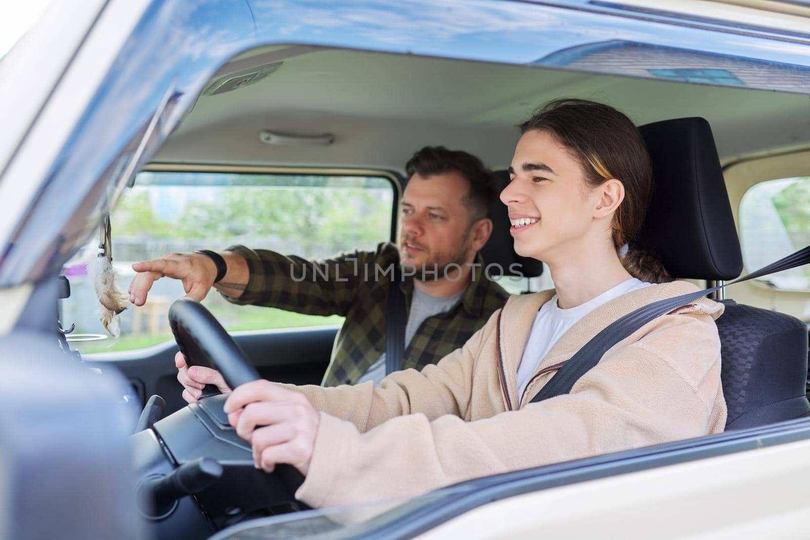 Father teaching his teenage son to drive. Family, relationship middle aged parent teenager, friendship of father and son