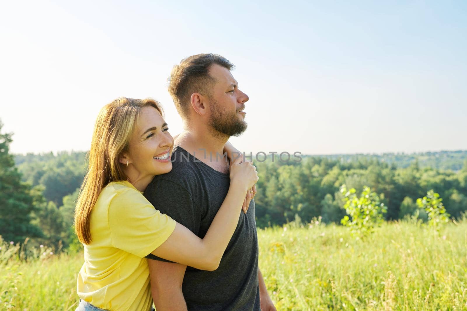 Portrait of happy middle-aged couple on summer sunny day. Beautiful people man and woman embracing in nature, family, happiness, holidays, joy concept. Copy space
