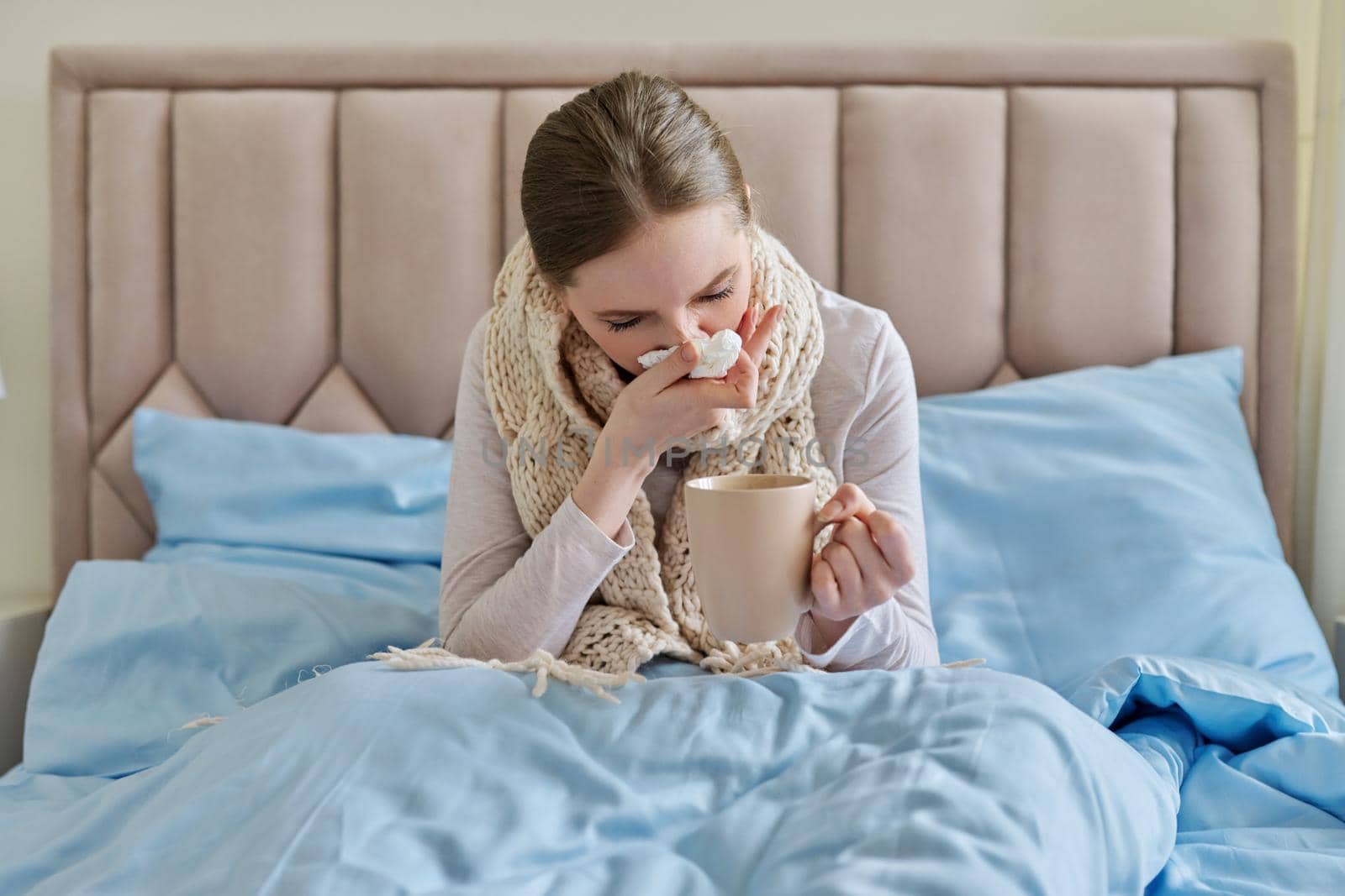 Sick young woman in bed with handkerchief and cup. Flu season, seasonal viral diseases, health, medicine, get sick at home, bed rest, people concept