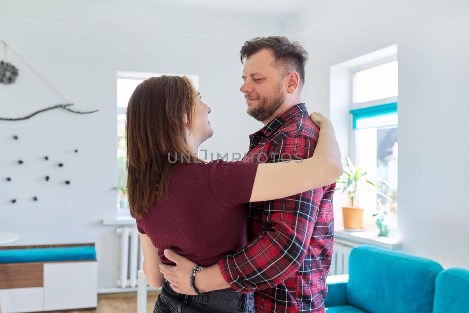 Happy romantic middle aged couple in love dancing, husband and wife dancing at home in living room, in home casual clothes. Relationships, lifestyle, communication, home life, middle-aged people
