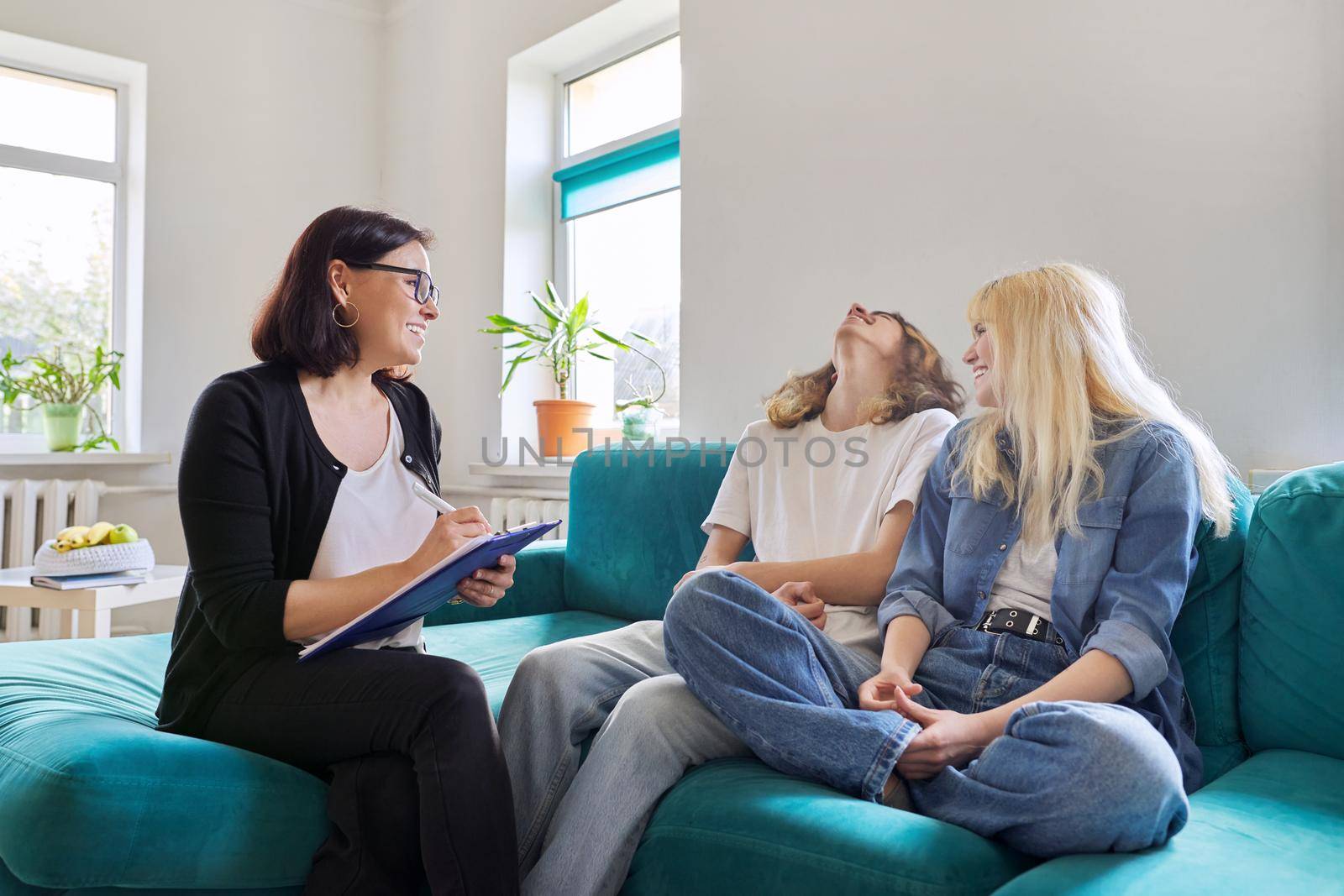 Professional female social worker, teacher, counselor, psychologist talking with teenagers by VH-studio