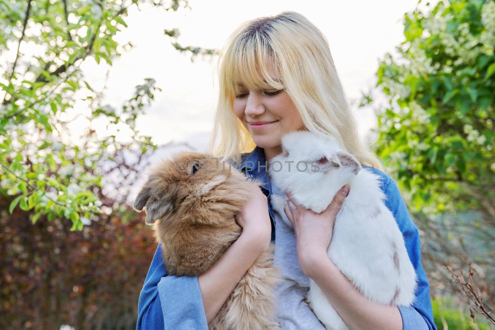 Beautiful smiling girl teenager with a couple of decorative rabbits by VH-studio