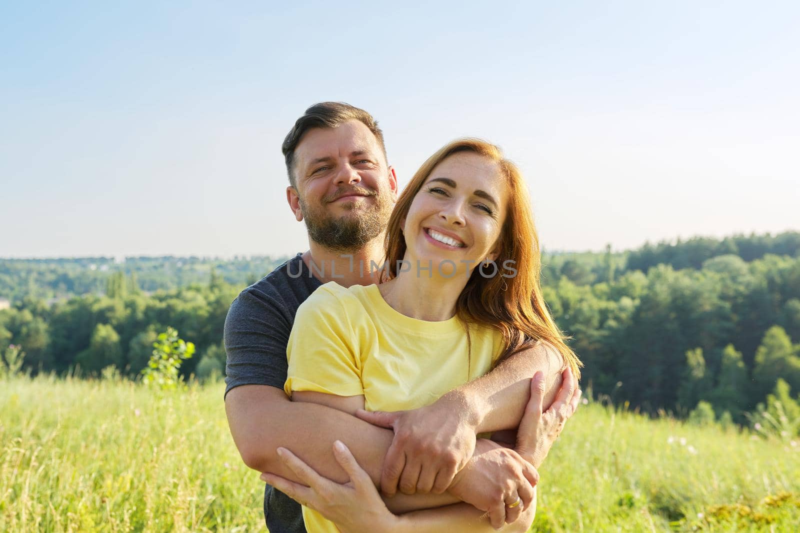 Portrait of happy adult couple on summer sunny day. Beautiful people man and woman embracing in nature, family, happiness, holidays, joy concept