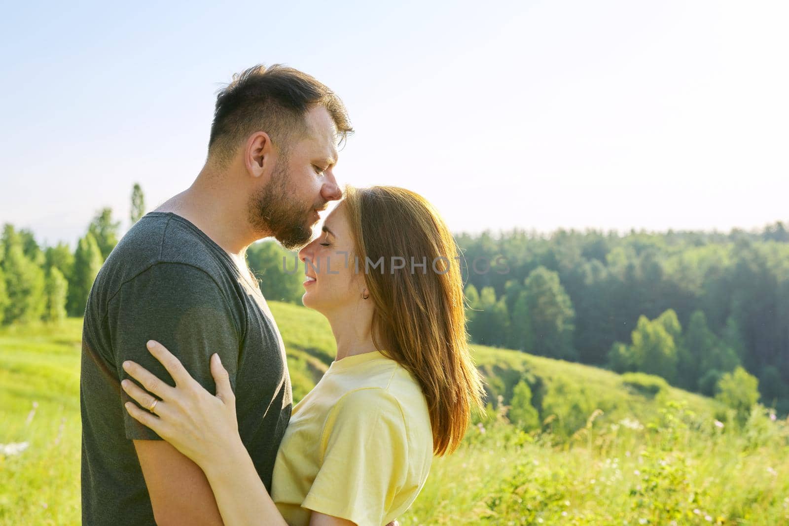 Happy adult couple in love. Man and woman in profile, romantic kiss, nature sky meadow summer background, copy space