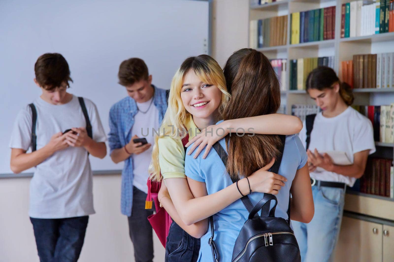 Back to school, to college. Two school girlfriends teenagers are welcome, meeting, smiling, rejoicing. Library classroom schoolroom interior. Adolescence, lifestyle, communication, friendship concept