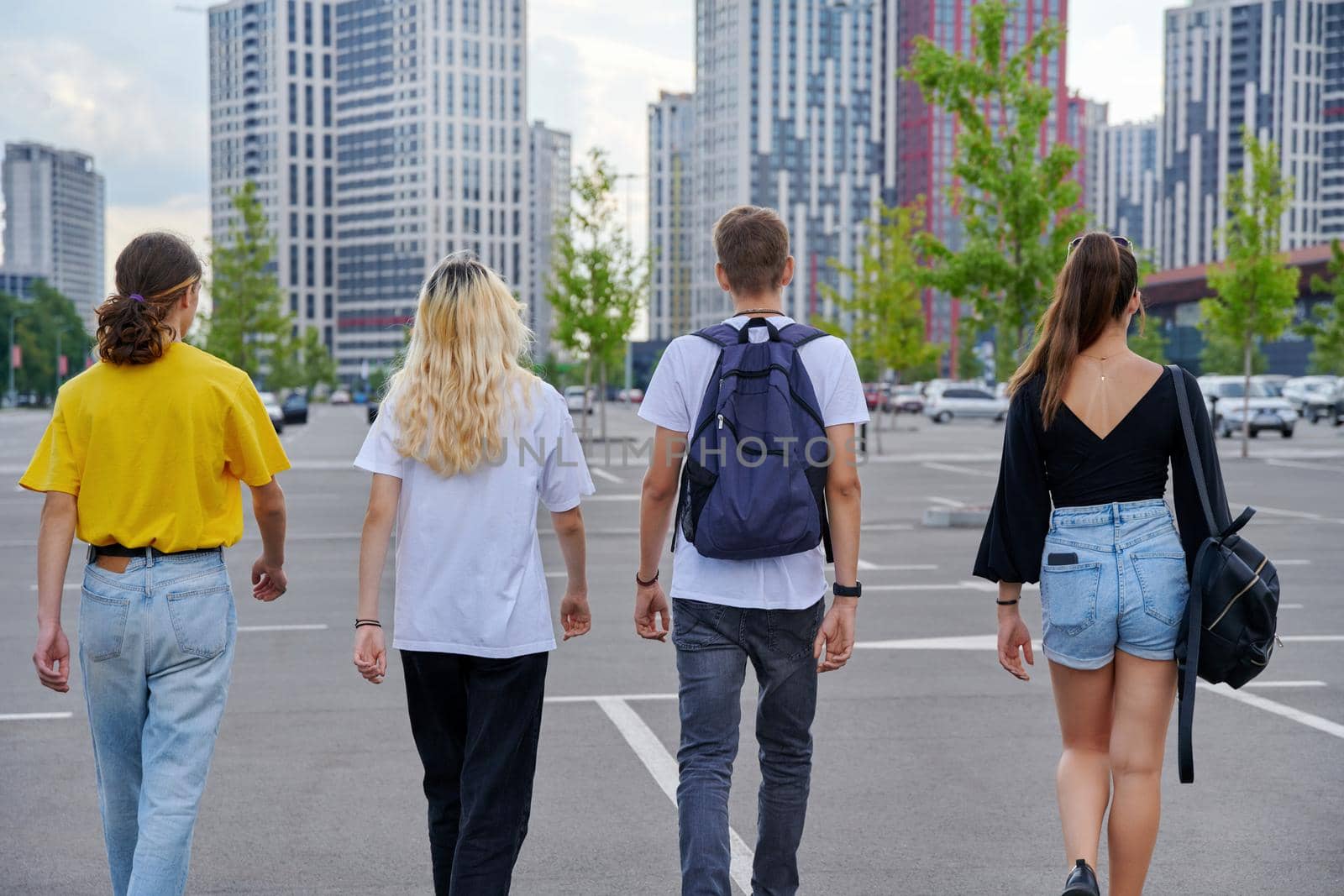 Group of teenagers walking together, back view, urban style, modern city background. Trending youth, lifestyle, friendship, high school, college, adolescence concept