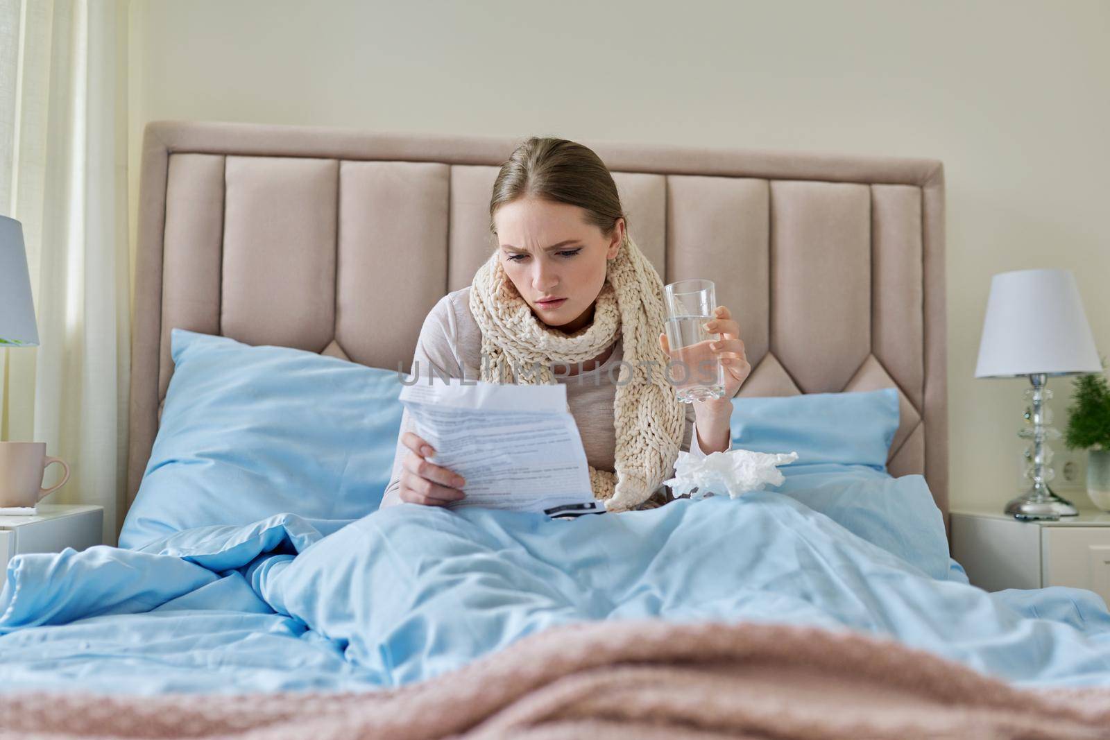 Young sick woman at home in bed, female reading instructions for medication by VH-studio