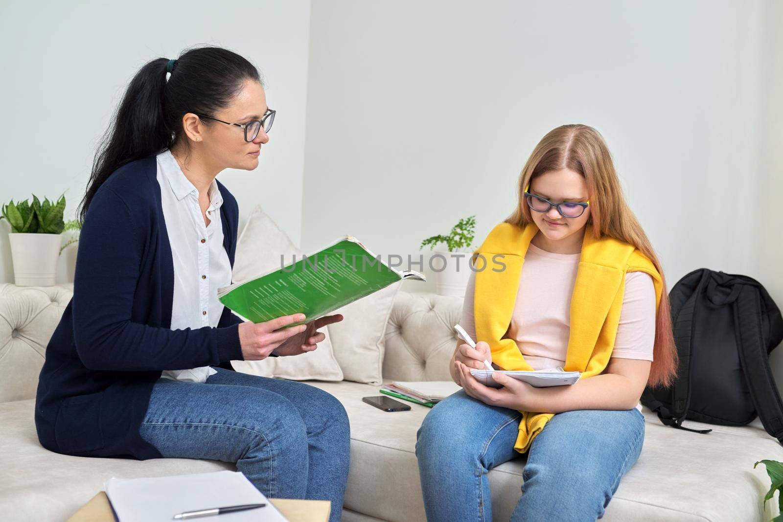 Female teacher studying individually with teenage girl, instructor testing young student