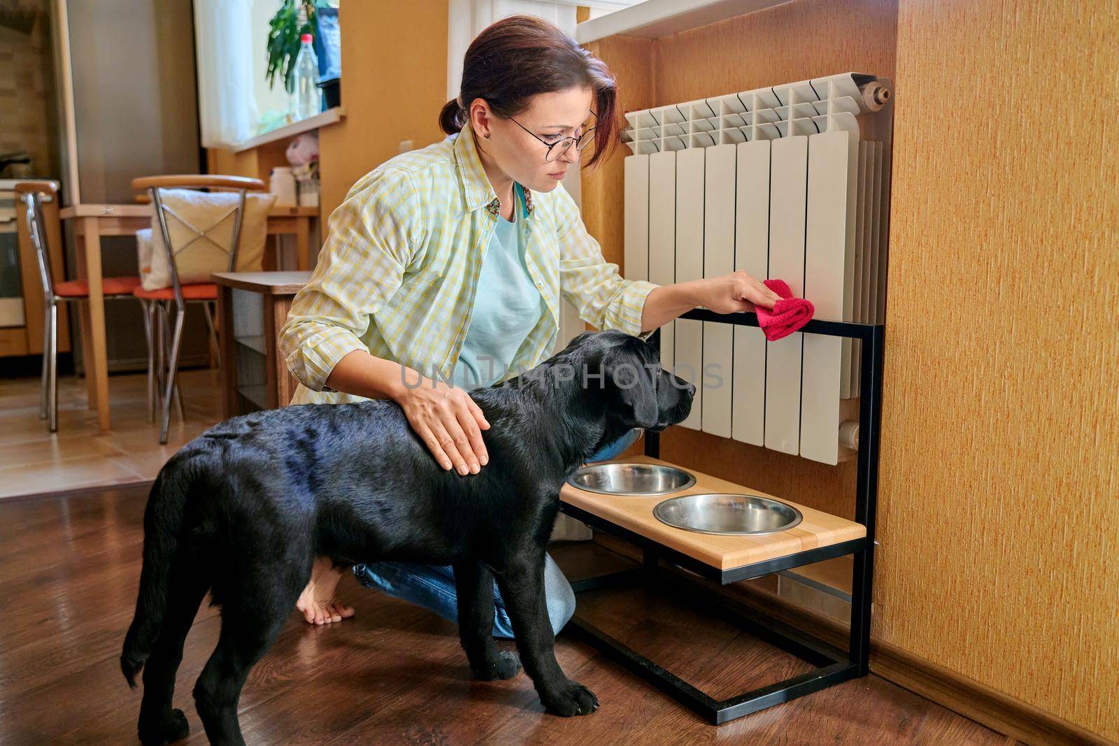 Middle aged woman and pet dog at home in kitchen interior by VH-studio