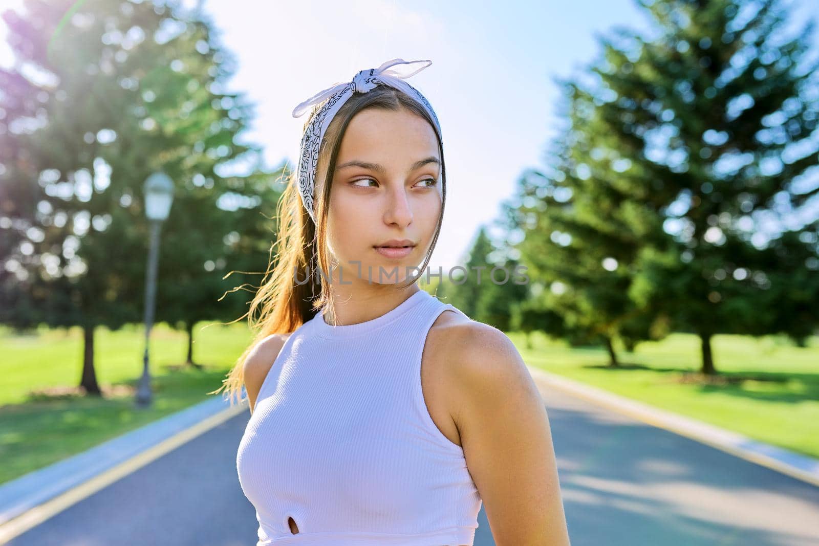 Portrait of beautiful smiling young female outdoors. Hipster teenager on sunny summer day, on the road in the park. Teens, people, age, youth concept