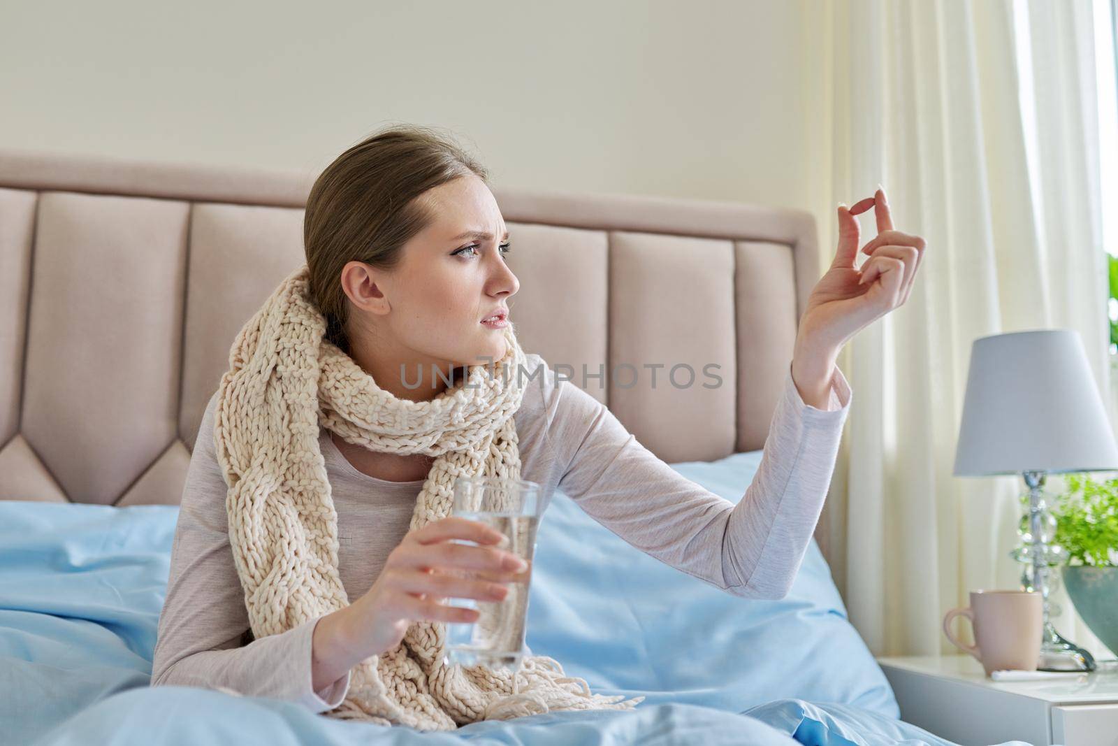 Sick woman with glass of water and pills in her hand by VH-studio