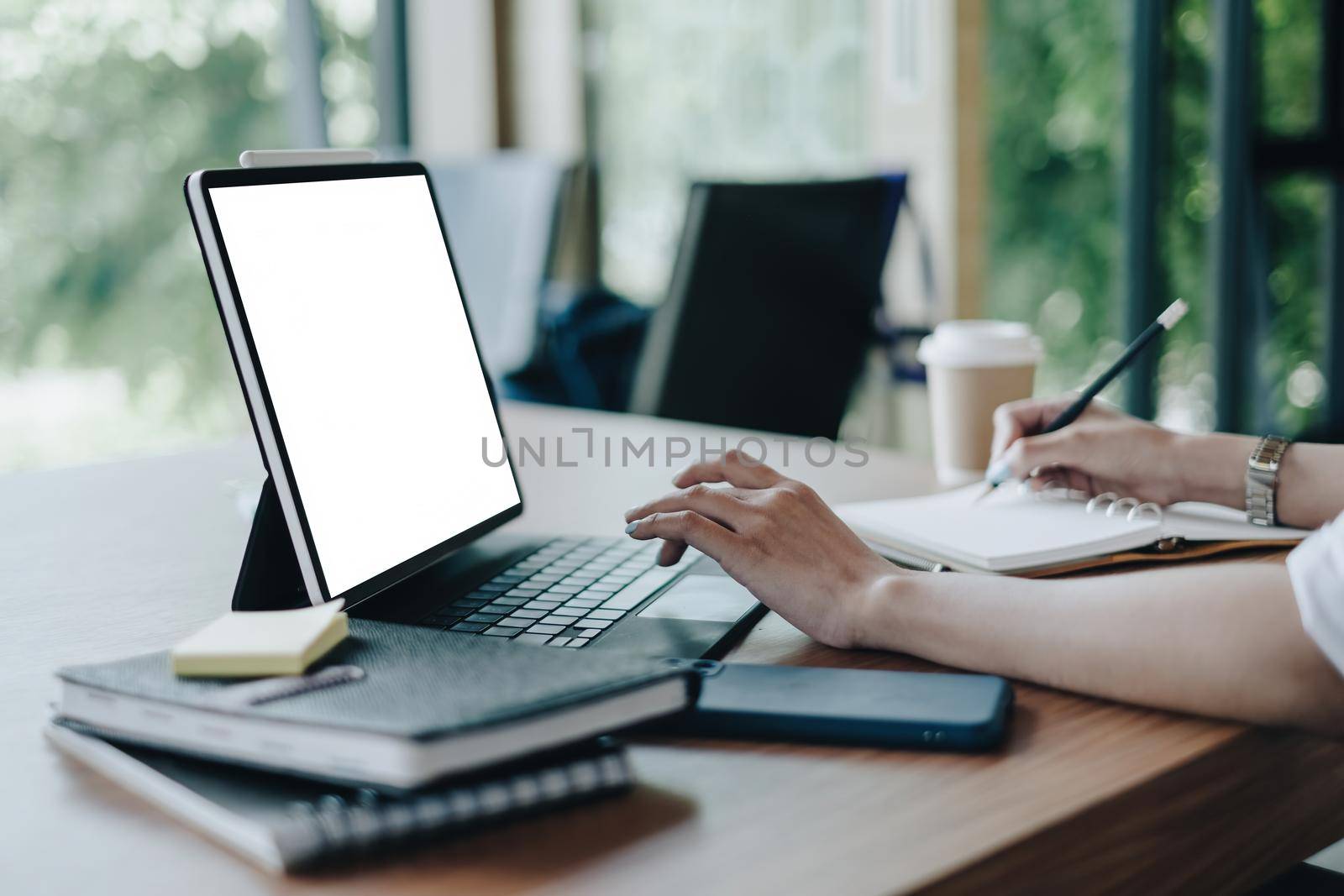 Mockup image of a digital tablet with white blank screen on wooden desk