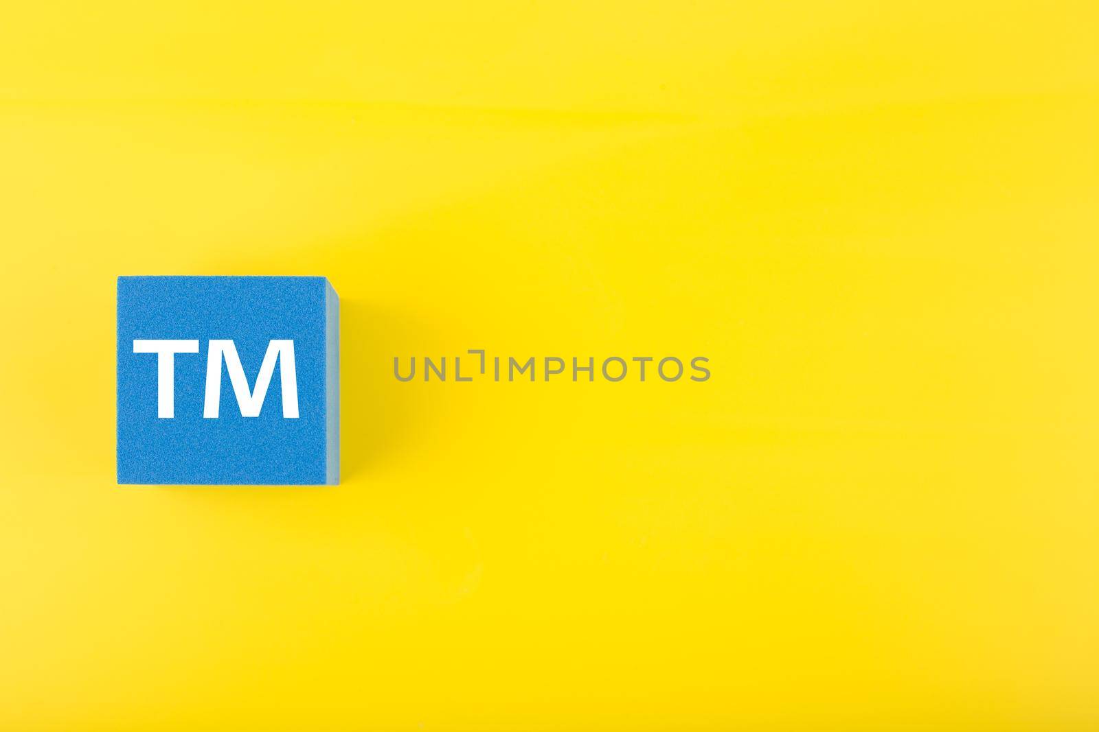 TM trademark sign on blue toy cube on yellow background with copy space by Senorina_Irina