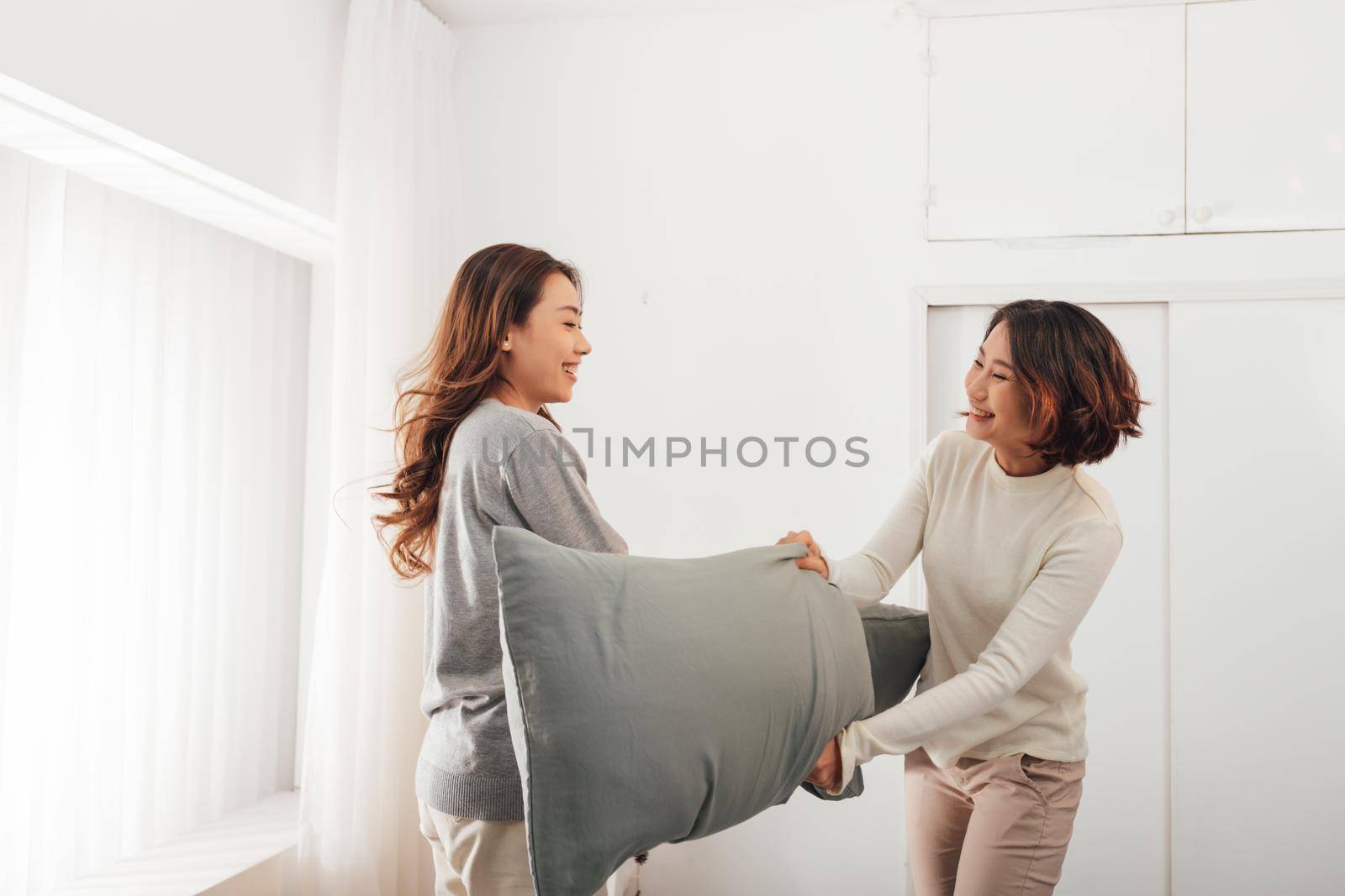 Beautiful sexy two girls having fun in bedroom, pillow fight.