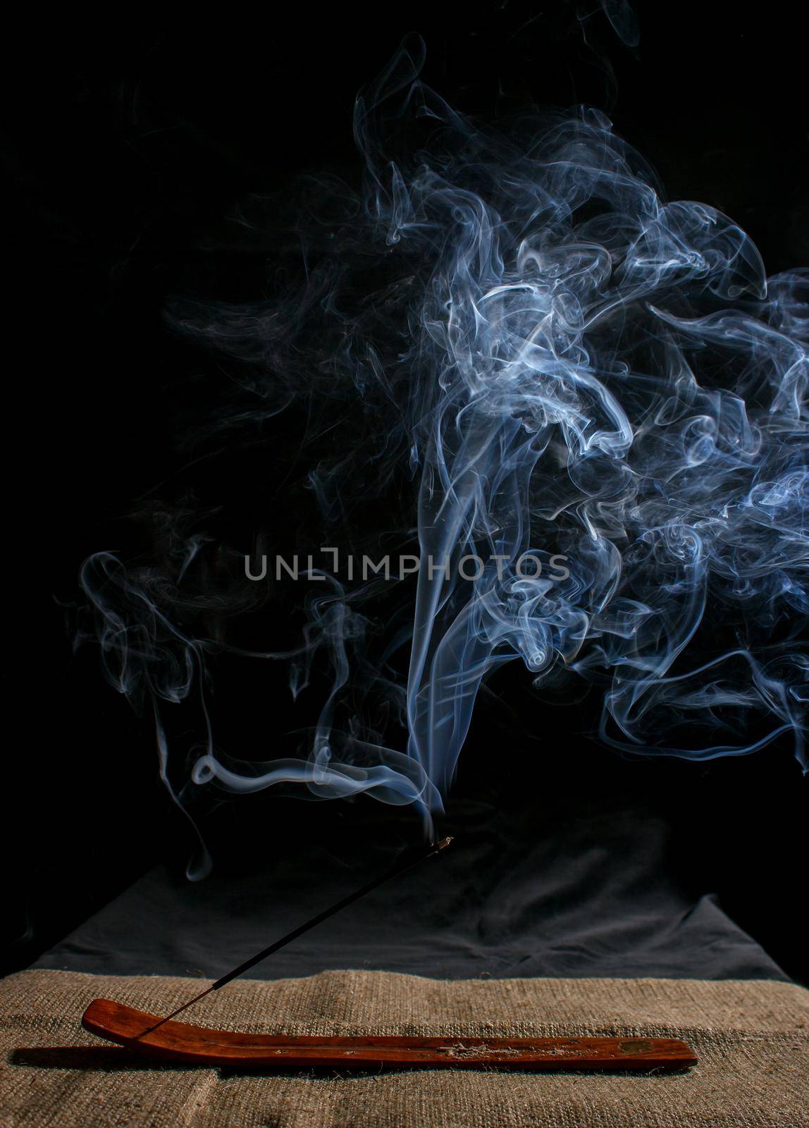 indian incense stick with smoke on black background indoor closeup