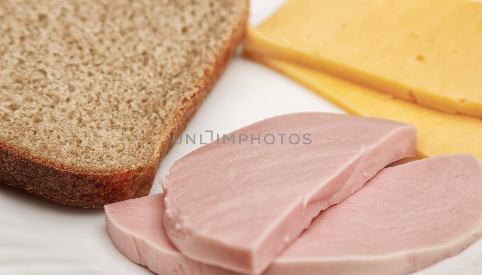 slices of cheese bread and sausage on a plate on wooden table. indoor closeup