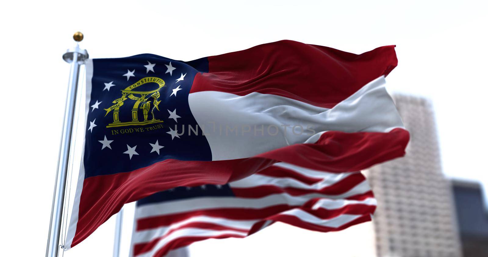 the flag of the US state of Georgia waving in the wind with the American stars and stripes flag blurred in the background by rarrarorro