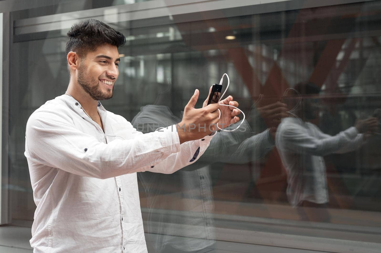 Young man smiling happy doing video call using smartphone at city. by HERRAEZ