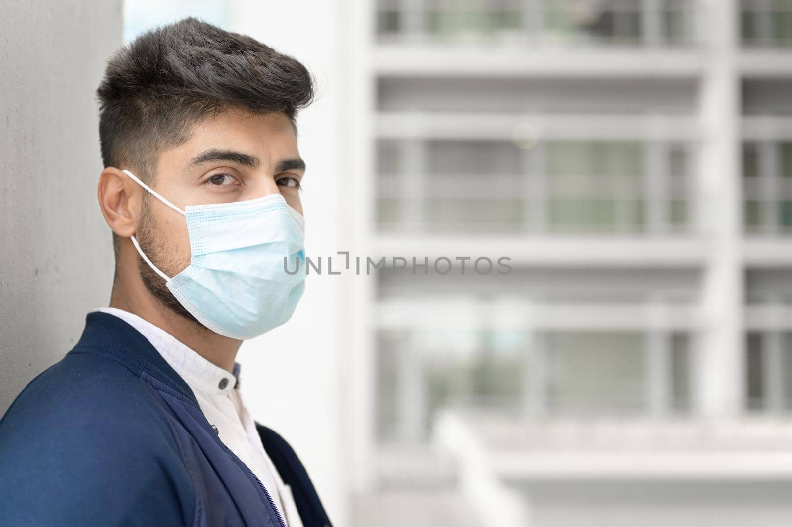 Portrait of a Handsome man in medical mask looking to camera at city. Handsome young man standing outdoors in medical mask. Coronavirus concept. by HERRAEZ