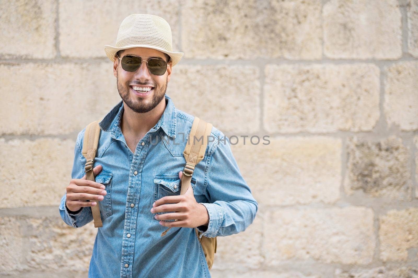 Stylish traveler bearded man in hat posing looking at camera, travel and wanderlust concept. High quality photo