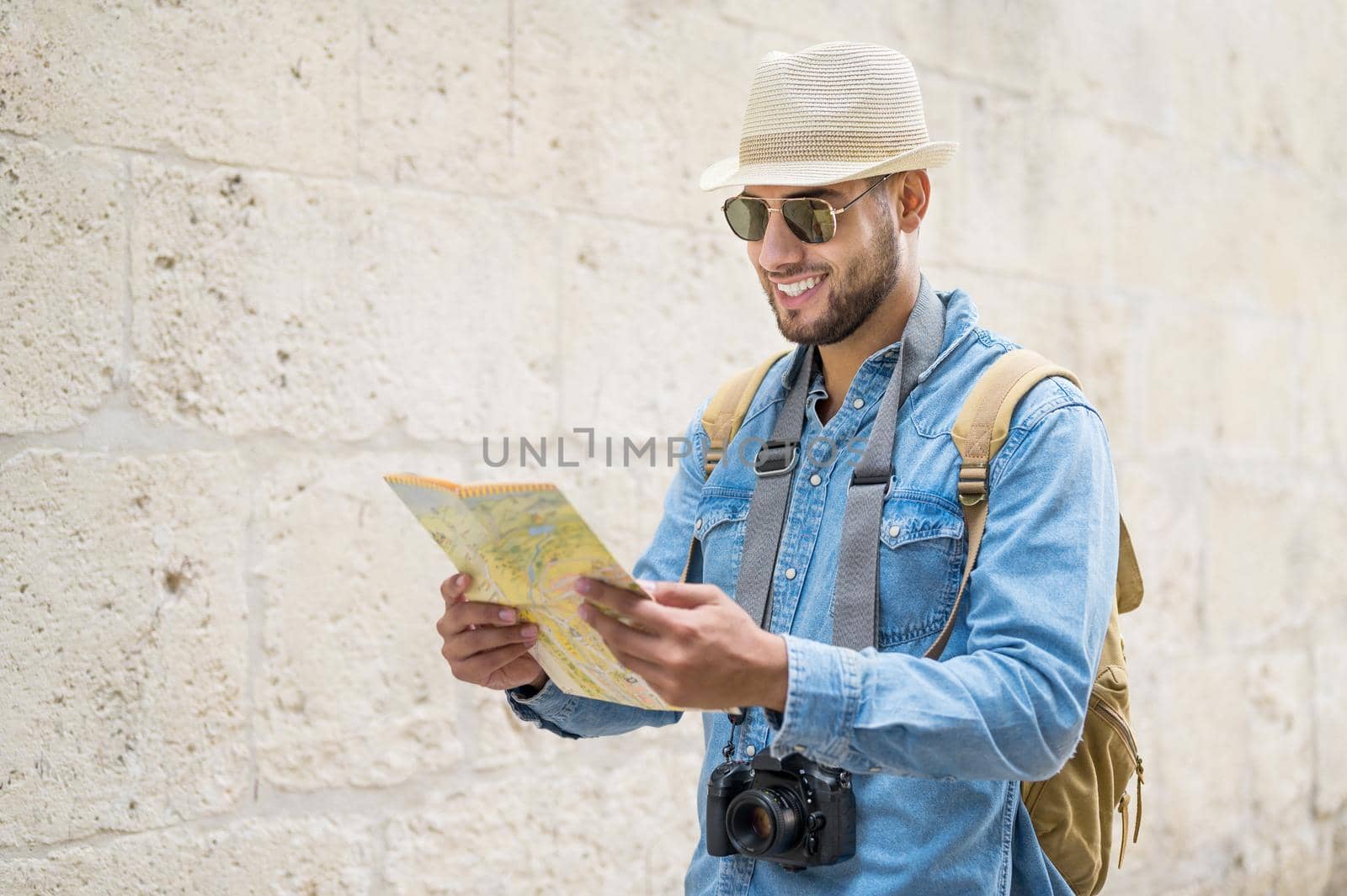 Young handsome man with tourist map looking around the city street. High quality photo.