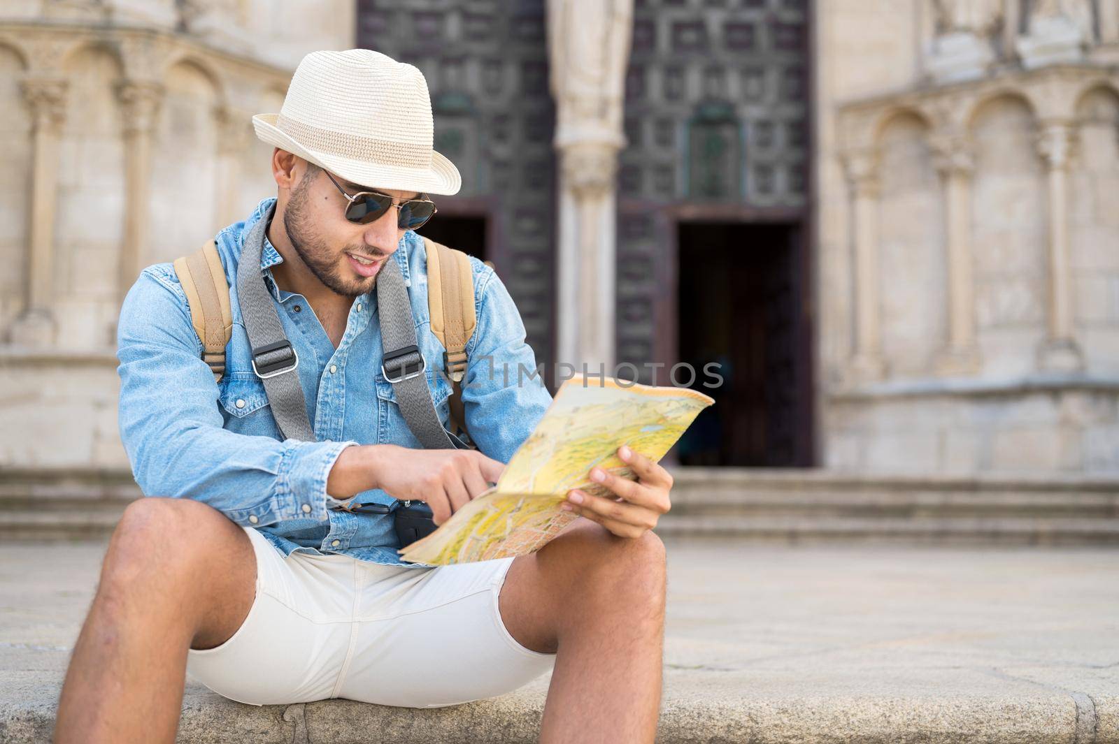 Handsome tourist man pointing at map searching the direction of destination. Travel concept. Trip, backpacker tourist. High quality photo