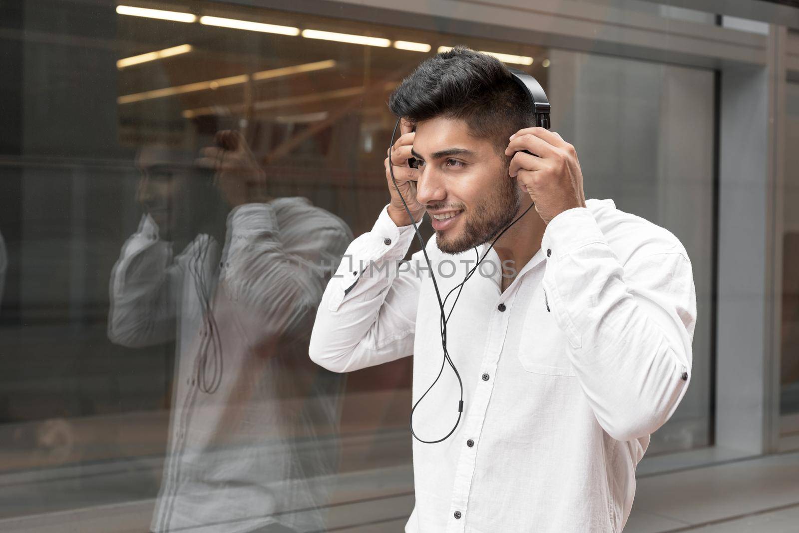 Handsome young man smiling and listening music on the street. High quality photo