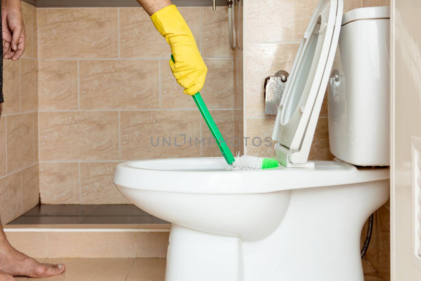 Using a plastic brush to scrub the toilet bowl. by wattanaphob