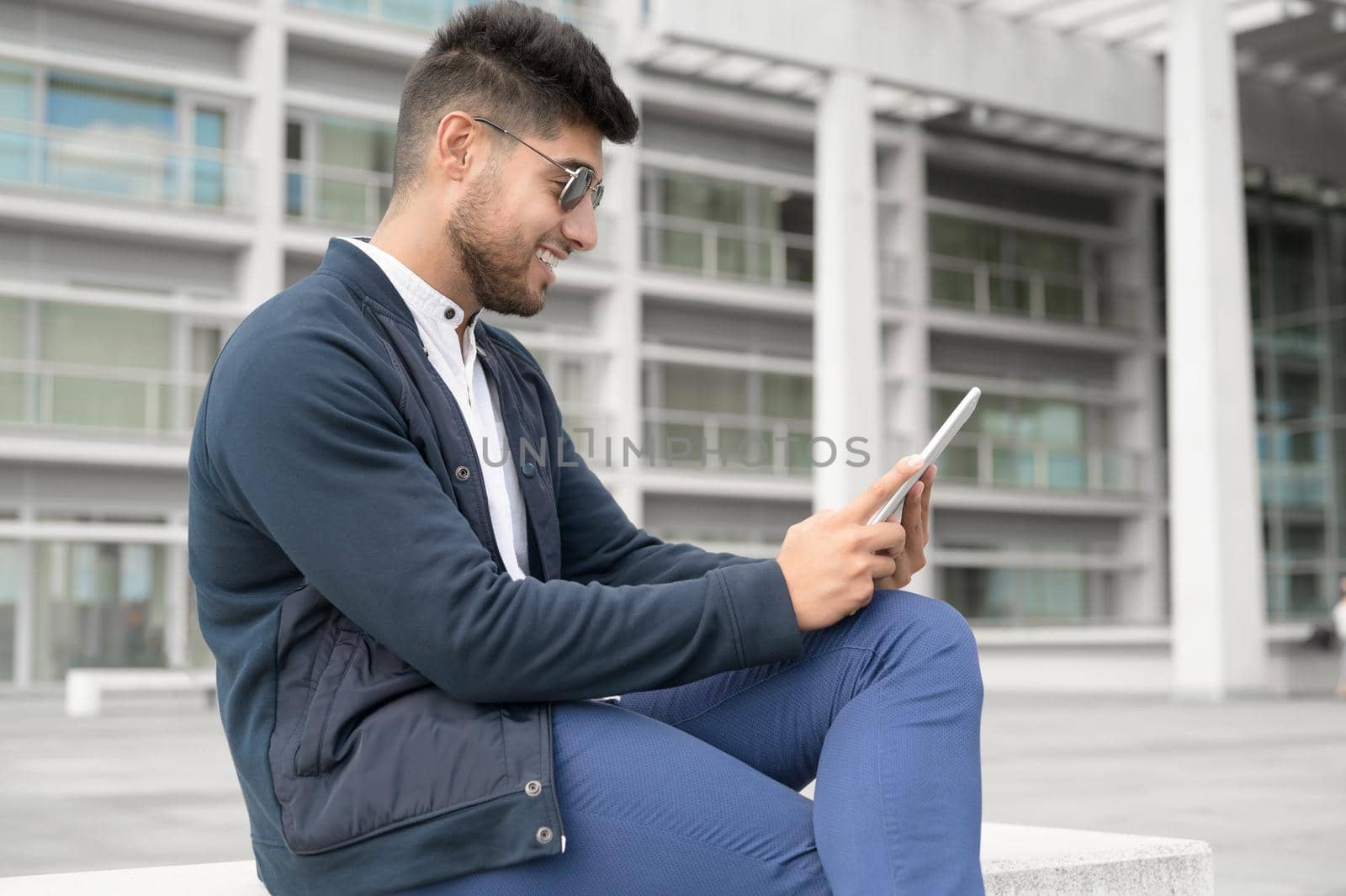 Young handsome men using smartphone in the city. Smiling young man texting on his mobile phone. Coffee break. Modern lifestyle, connection, business concept. High quality photo.