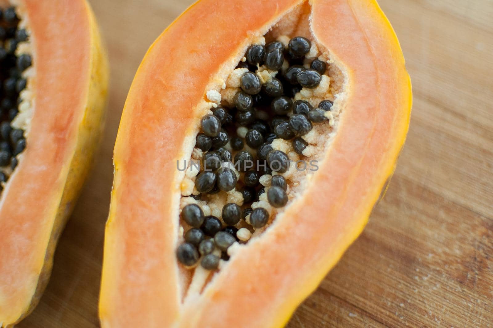 Fresh organic ripe papaya fruit cut in half on a wooden board. Exotic fruits, healthy eating concept.