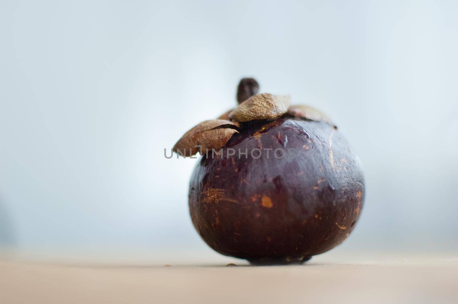Mangosteen fruit with dark purple skin on wooden table, the queen of exotic fruits. Healthy eating concept.