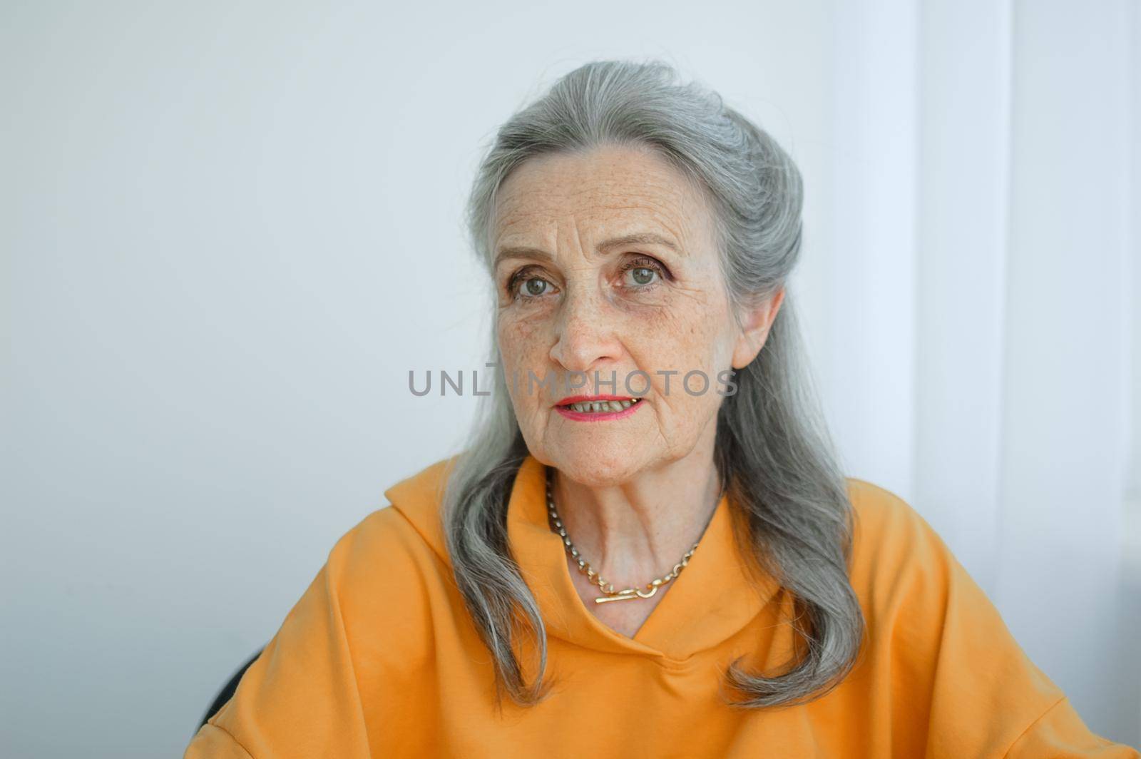 Portrait of beautiful old grandmother with grey hair and face with wrinkles looking at the camera, mothers day, happy retirement.