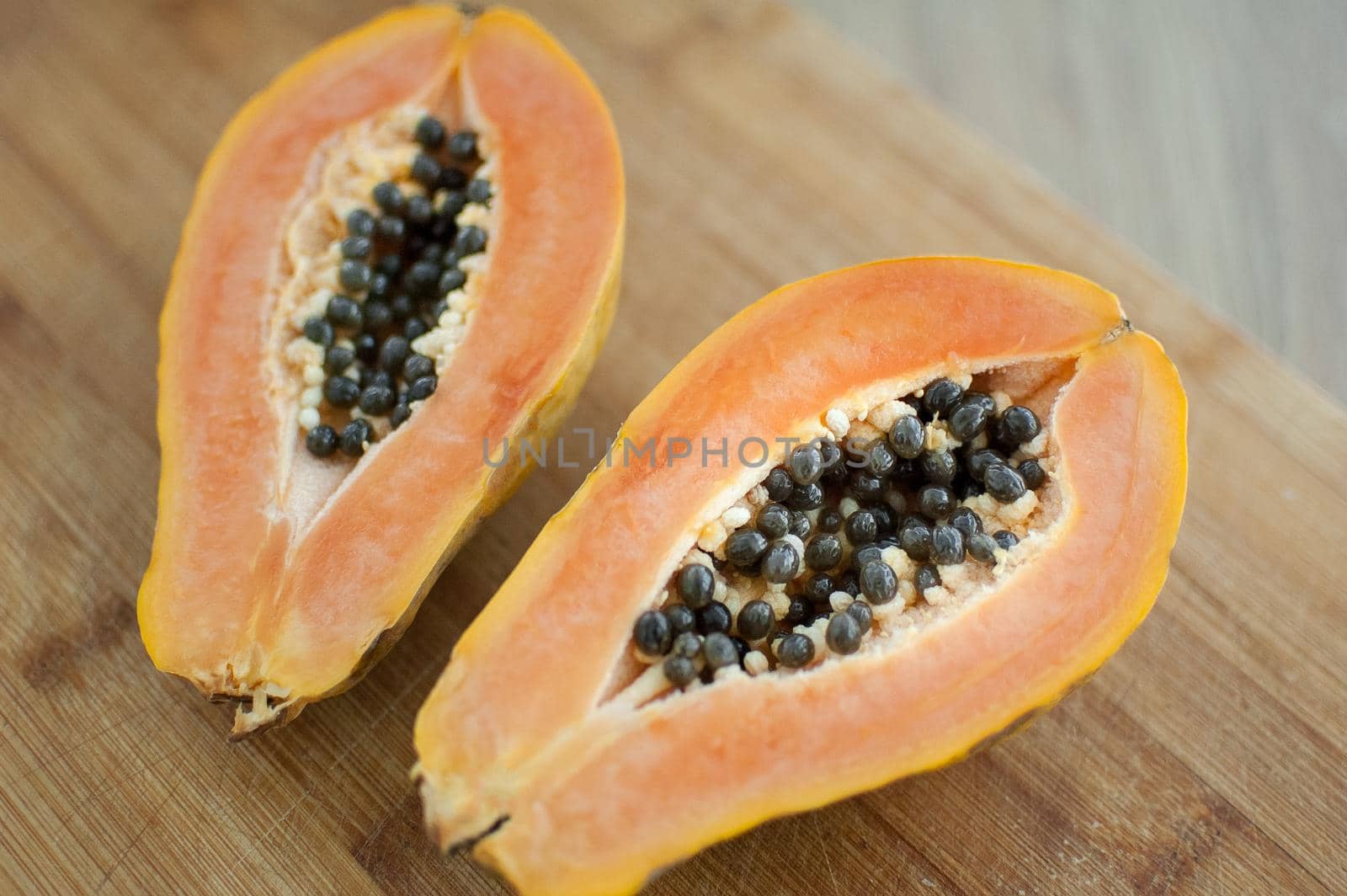 Fresh organic ripe papaya fruit cut in half on a wooden board. Exotic fruits, healthy eating concept by balinska_lv