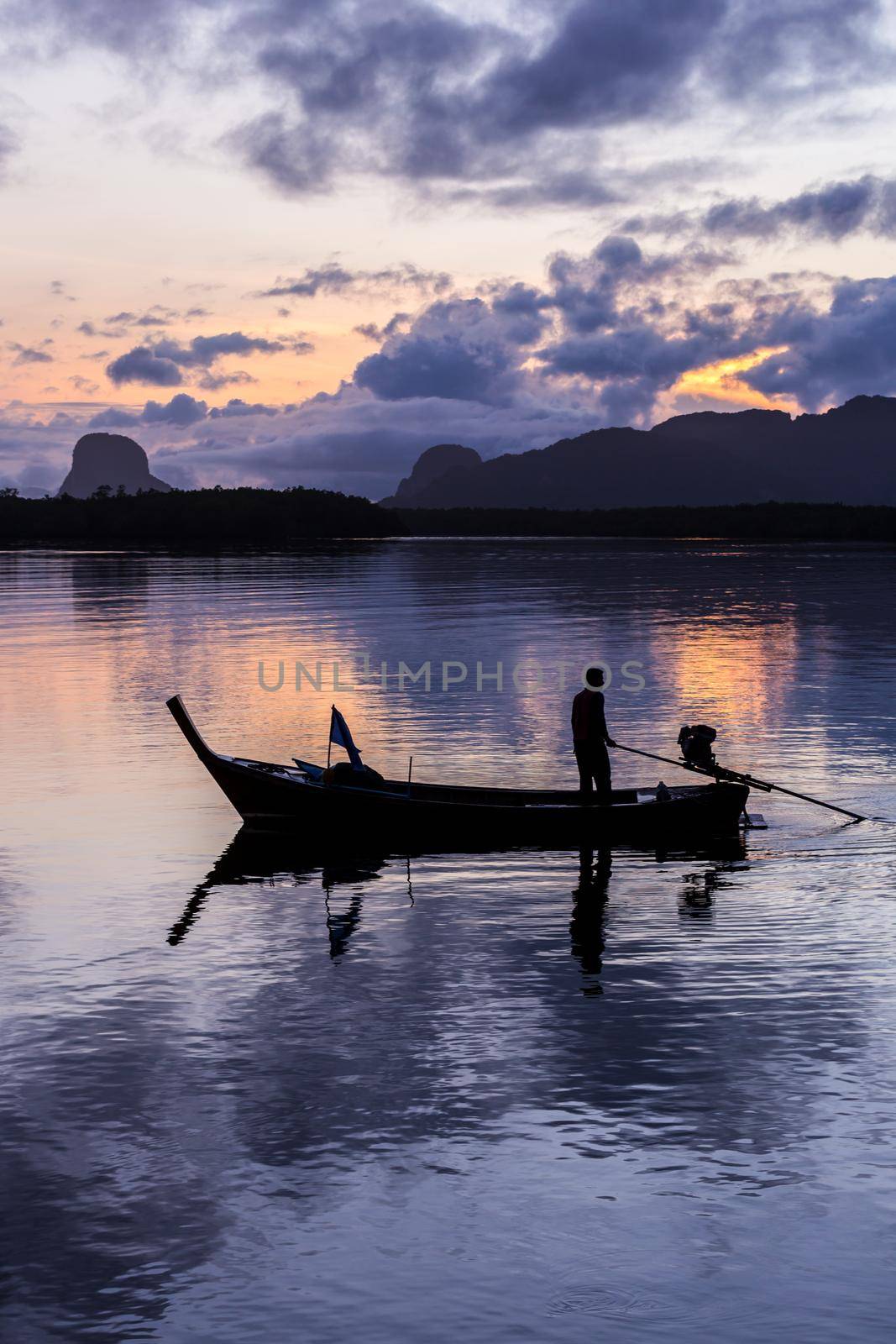 silhouette fisherman in fishing boat on sea at sunrise.