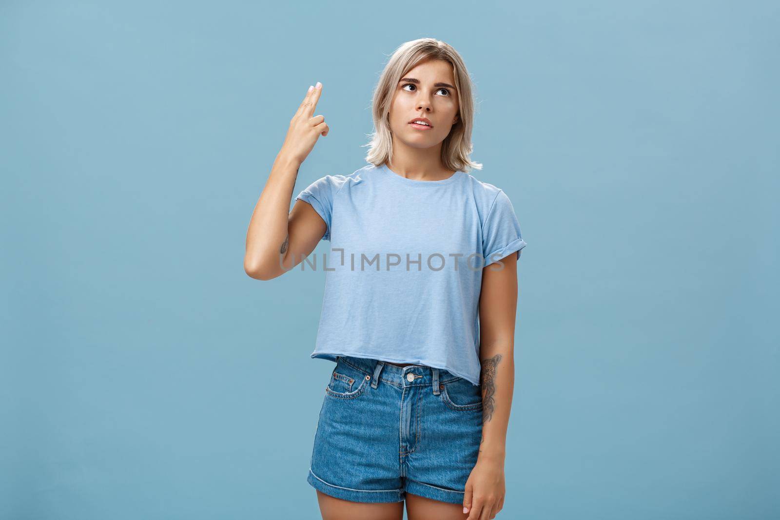 Stop teaching me how live my life. Portrait of irritated displeased attractive blonde female in denim shorts and casual t-shirt rolling eyelids from annoyance showing gun gesture as if blowing brains.