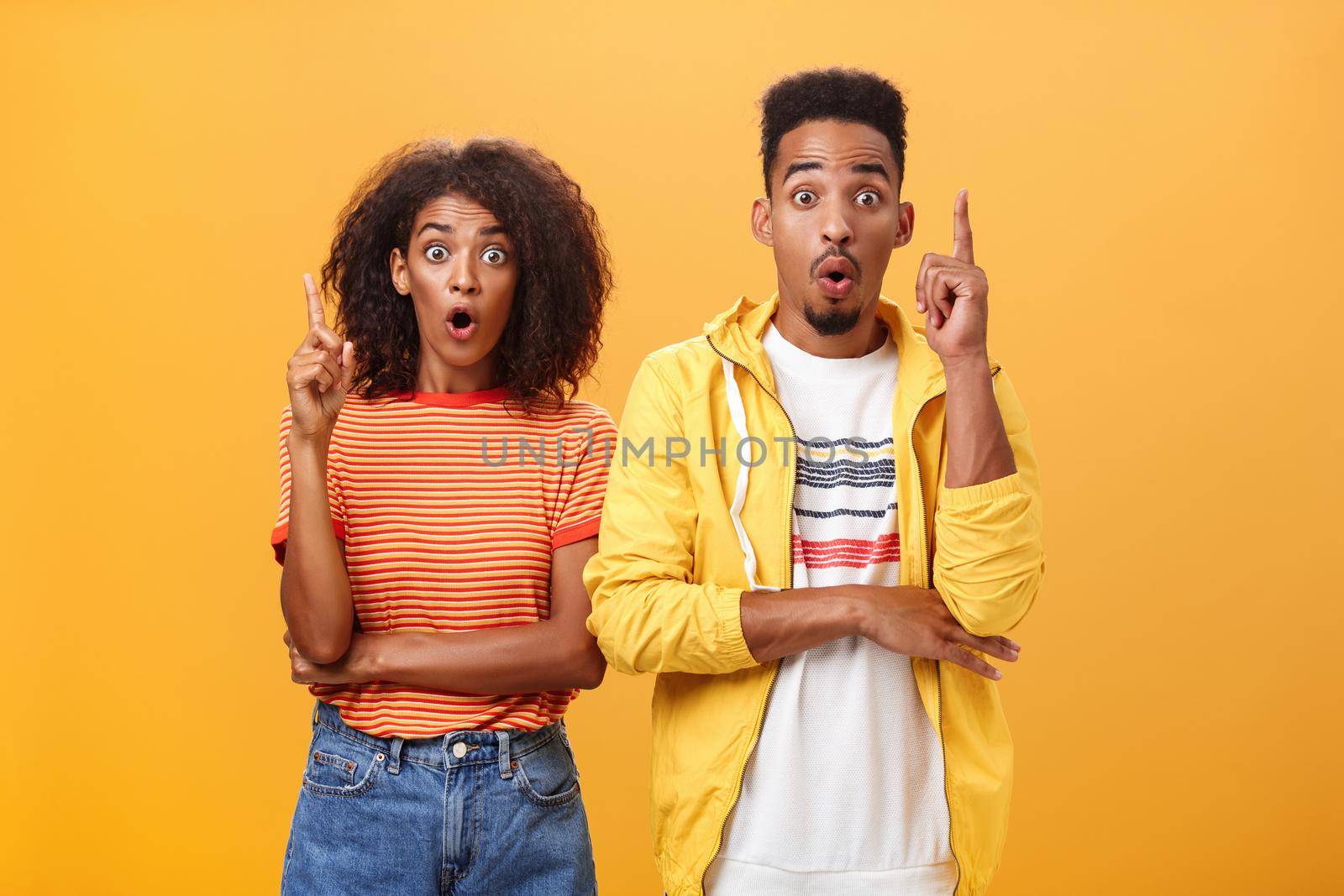 The both got perfect idea at same time. Amazed and excited creative charismatic african american man and woman raising index fingers in eureka gesture opening mouth while adding suggestions. Copy space