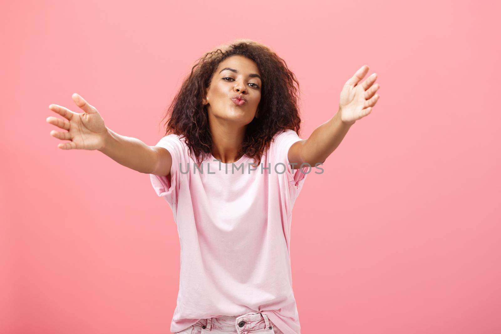 Come closer let me hug you. Portrait of passionate confident and happy good-looking african american woman with curly hairstyle folding lips pulling hands towards camera to cuddle and give kiss. Relationship and feelings econcept