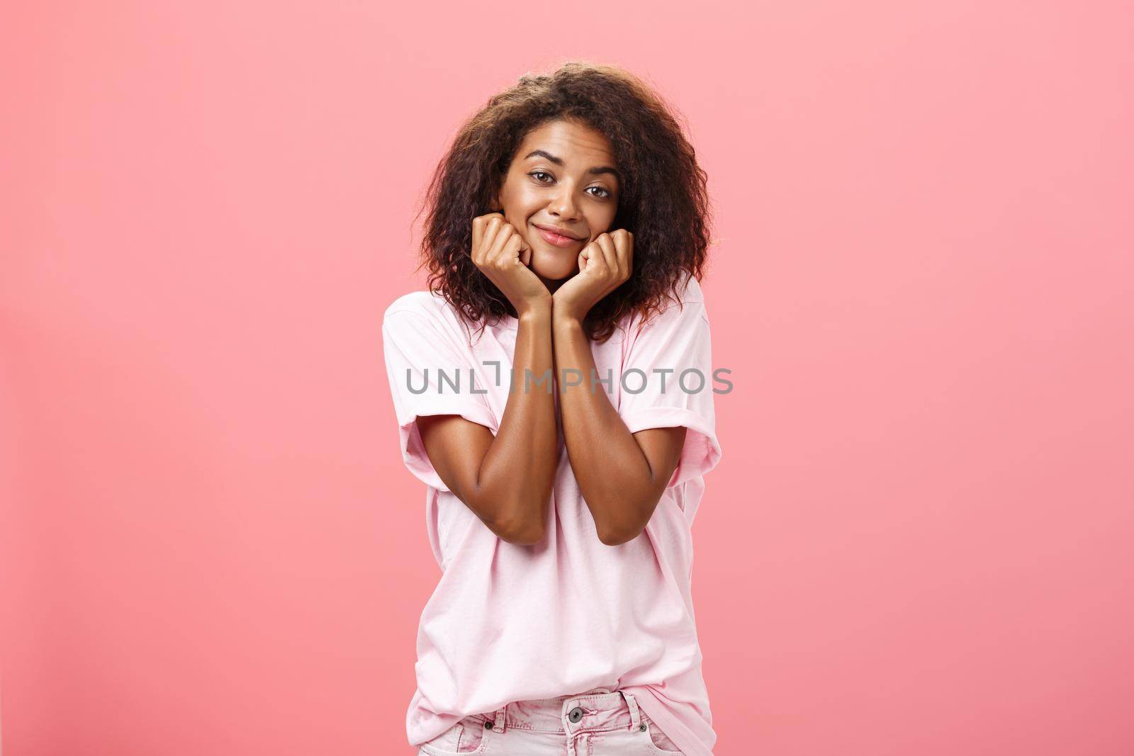 Dreamy nostalgic african american girlfriend with curly hairstyle sighing leaning head on palms and smiling gently as if imaging or gazing at boyfriend with affection having feelings for friend. Lifestyle.